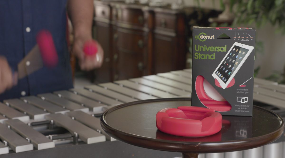 A phone propped hands-free in a GoDonut stand on a kitchen counter