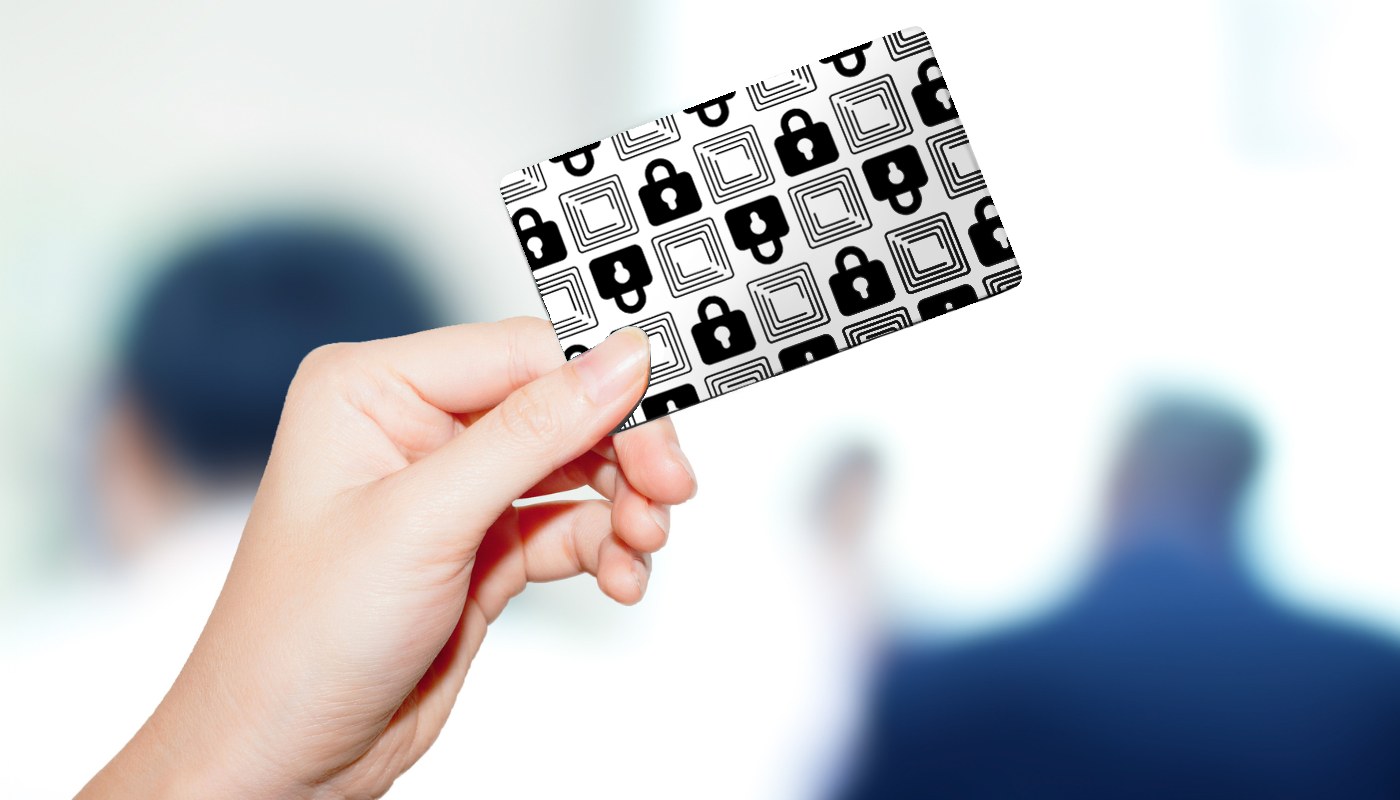 A hand holding the fully visible Wallet Defender RFID-blocking card in close-up