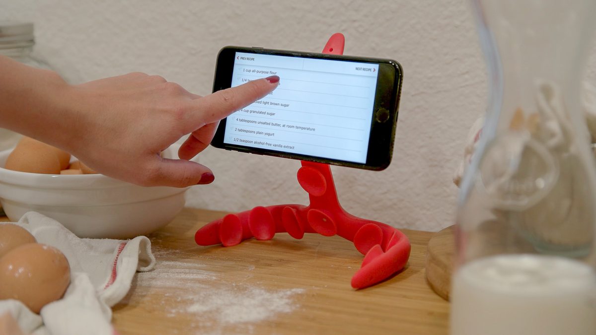 The flexible Tenikle phone mount suction-cupped to a surface holding a phone