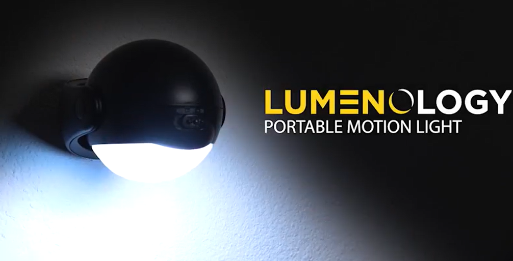 A Lumenology portable motion light mounted on a wall, glowing in the dark